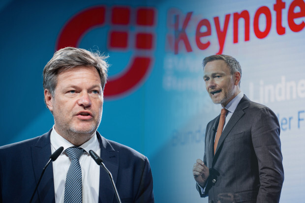 Robert Habeck und Christian Lindner fegen Laub im Wald